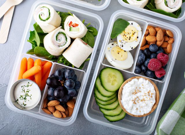 proteinreiche Snack- oder Lunchbox mit Hüttenkäse, Gurken, Mandeln, Beeren, hartgekochtem Ei, Truthahn-Wraps, Karotten und Ranch