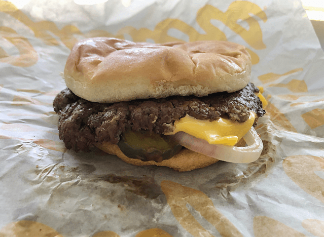 ein Burger mit Käse und Gurken auf Papier. 