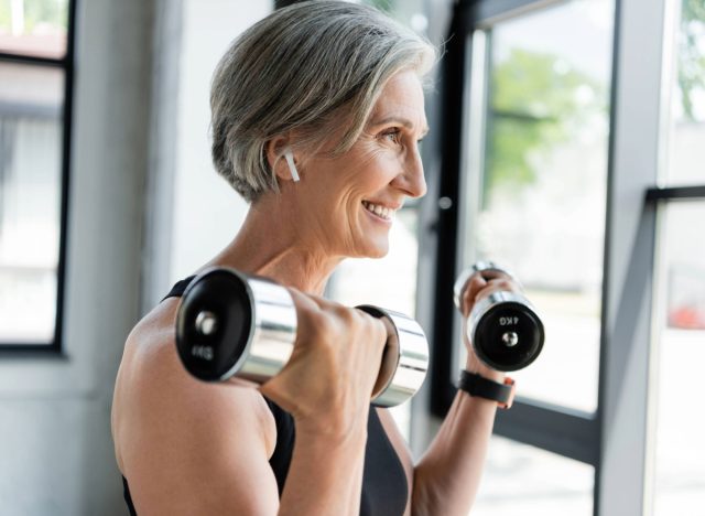 Glückliche Frau beim Gewichtheben, Konzept, wie viele Tage pro Woche man trainieren sollte, um Ergebnisse zu erzielen